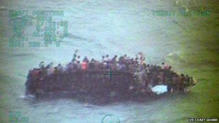Handout image provided by the US Coast Guard showing approximately 100 Haitians sitting on the hull of a 40-foot sail freighter after it grounded and capsized on 26 November, 2013, 15 nautical miles southwest of Staniel Cay, Bahamas in the Caribbean Sea