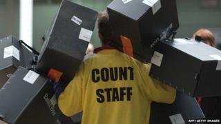 File photo of a man carrying ballot boxes as he helps to count votes