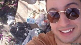 A man poses in front of some rubbish