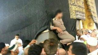 A policeman leans against a sacred building in Mecca