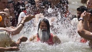 Hindu devotees splash water on a Hindu Sadhu during the Kumbh Mela festival in Haridwar