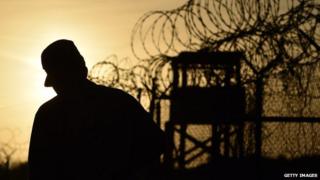 A soldier is silhouetted against the sky on the Guantanamo Bay detention facility.