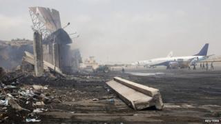 Planes near a section of a damaged building (L) at Jinnah International Airport, after Sunday's attack by Taliban militants, in Karachi