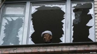 A man looks out of the broken window of his home in a residential building which was damaged by what locals say was overnight shelling by Ukrainian forces in the eastern town of Slaviansk