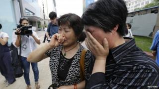 A woman (L), whose son, daughter-in-law and grandson were aboard the missing Malaysia Airlines flight MH370, cries in Beijing June 11