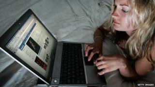 A woman browses Facebook on her laptop.