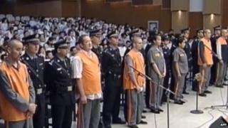 This screen grab taken from state broadcaster China Central Television (CCTV) footage shows eight prisoners (in orange and brown) standing at attention upon their arrival at the Intermediate People's Court in the Xinjiang capital Urumqi, 16 June 2014, for the trial of those accused in the attack in October 2013 in Beijing's Tiananmen Square that killed two tourists