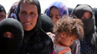 Displaced Iraqi women and children fleeing violence in Northern Iraq stand in line at a refugee centre near Arbil.