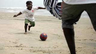 A child plays football with his father at the beach in Accra, Ghana, on 6 February 2008
