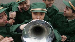 Chinese Army recruits watch as a colleague plays a trumpet