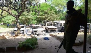 Kenya police observe the remains of burnt-out cars at a police station in Mpeketoni on 16 June 2014