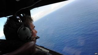 In this file photo taken on April 13, 2014 from a Royal New Zealand Airforce P-3K2-Orion aircraft, co-pilot and Squadron Leader Brett McKenzie helps to look for objects during the search for missing Malaysia Airlines flight MH370