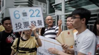 Demonstrators supporting the Occupy Central movement display placards asking residents to cast ballots for the 22 June during a protest outside Beijing's representative office in Hong Kong, on 11 June.