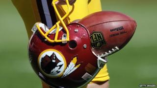 A player carries a Redskins helmet with a football in it.
