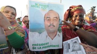 Supporters of Mauritania's president and candidate to his succession Mohamed Ould Abdelaziz hold campaign posters during a meeting in Akjoujt