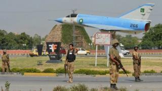 Pakistani soldiers patrol a street near a retired Pakistan Air Force Dassault Mirage III aircraft, on display as a gate guardian, near Peshawar International Airport on June 26, 2014