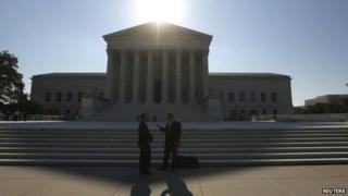Two men talk as the sun rises over the Supreme Court in Washington 23 June 2014