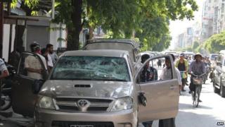 Local people hang around a damaged vehicle on a street of Mandalay in central Myanmar on 2 July 2014.