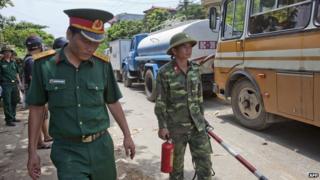 Vietnamese soldiers working at the scene of a helicopter crash walk past backed-up traffic in the Thach That district in the western parts of Hanoi on 7 July, 2014