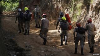 Firefighters walk towards a gold mine affected by a landslide to join rescue operations for eight miners who remain trapped in San Juan Arriba on 6 July, 2014