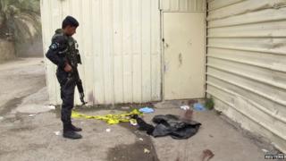 An Iraqi policeman looks at blood marks on the ground near an apartment building where the shooting occurred
