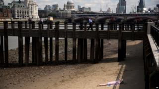 A woman sunbathes on the banks of the river Thames in London.