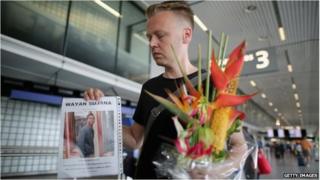 Dutchman Arthur Laumann holds a floral tribute and photograph of family friend Wayan Sujana of Bali