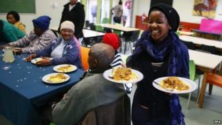 A South African girl serves a free meal to the elderly at the Masiphumelele Library, on the occasion of Mandela Day, in the impoverished community of Masiphumelele in Cape Town, South Africa, 18 July 2014.