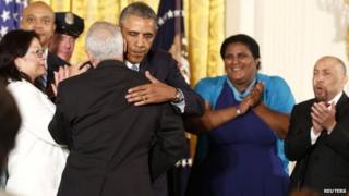 President Barack Obama is hugged after signing an executive order barring federal contractors from discriminating against gay and transgender workers (21 July 2014)