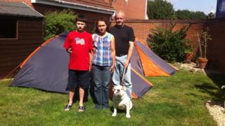 The Softely family and their dog standing in front of tents in their back garden