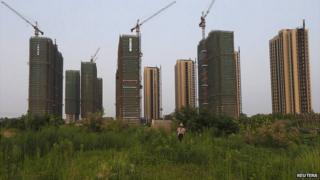 A farmer walks in front of a construction site of new residential buildings in Hangzhou, China