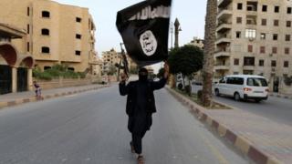 A member loyal to the Islamic State in Iraq and the Levant (ISIL) waves an ISIL flag in Raqqa on 29 June 2014.