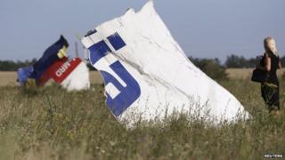 A woman takes a photograph of wreckage at the crash site of Malaysia Airlines Flight MH17 near the village of Hrabove (Grabovo), Donetsk region on 26 July 2014.