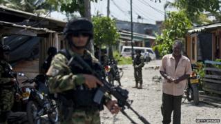 A man walks by Colombian marines patrolling during security operations in Buenaventura on 25 March, 2014.