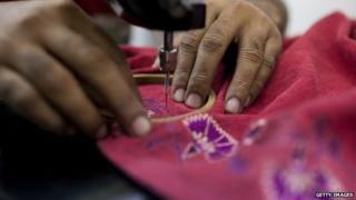 Hands of an Indian woman using a sewing machine