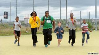Novlene Williams-Mills (second left), O'Dayne Richards (centre) and Kimberly Williams (second right) with some of the schoolchildren they met in north Glasgow