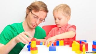 Father and son play with colourful block