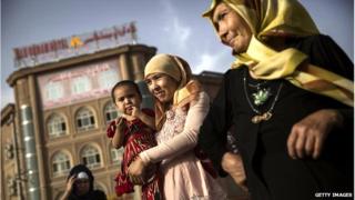 An Uighur woman walks with her baby at a market on 1 August 2014 in old Kashgar, Xinjiang Province, China.