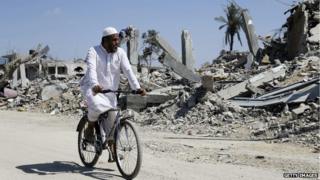 A Palestinian man rides past destroyed houses in Khuzaa town in southern Gaza