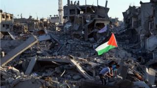 Residents walk through the rubble in the devastated neighbourhood of Shejaiya in Gaza City (7 August 2014)