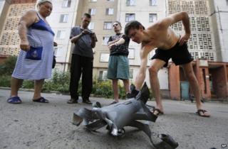Residents examine a shell fragment in Donetsk, 8 August
