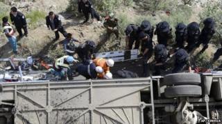 Rescuers try to pull out bodies and survivors from an overturned tour bus after it fell off a cliff in Nyemo County, Aug. 9
