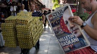 A man reads a newspaper in central Istanbul, Turkey, with a front page headline reading "President of the Nation"