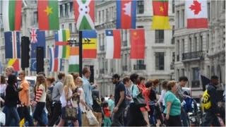 People crossing a London street with flags