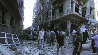 Residents inspect a site hit by what activists said were two air strikes by forces loyal to President Assad in Ghouta - 3 August 2014