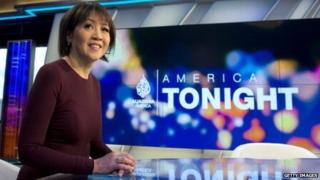 Presenter of Al Jazeera America in front of studio backdrop.