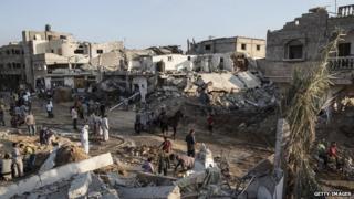 Palestinians walk through Khuza'a, Gaza