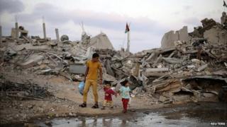 Palestinians walk next to the ruins of houses in the southern Gaza Strip - 18 August 2014