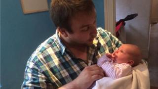 Sam Slater cradles baby