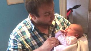 Sam Slater cradles baby